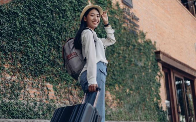 Traveler Wanita Bahagia dengan Ransel dan Bagasi