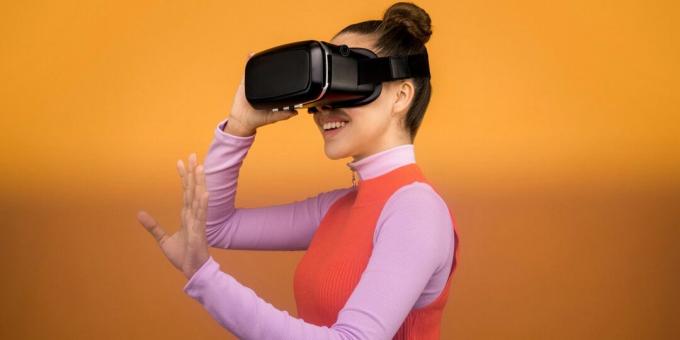 Wanita tersenyum sambil mengenakan headset realitas virtual hitam