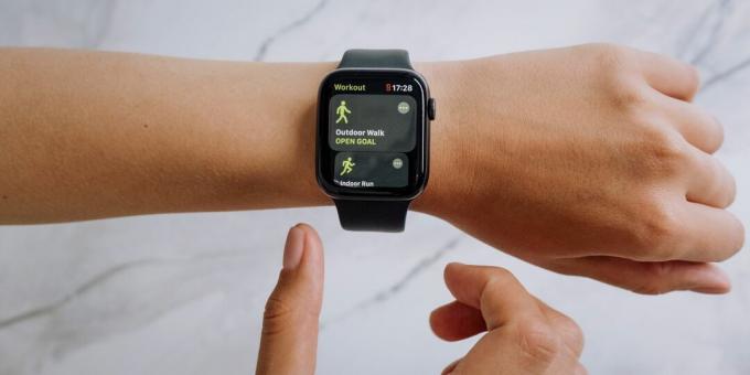 Apple Watch dengan tali jam olahraga yang menampilkan olahraga jalan kaki di luar ruangan